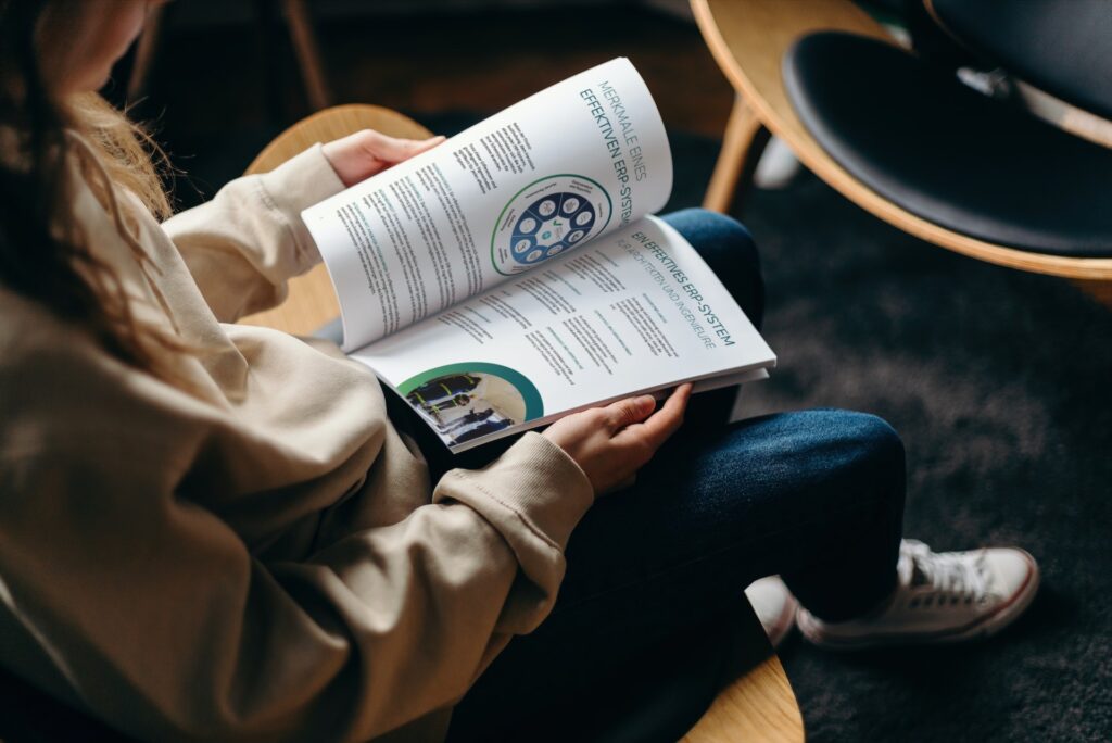 Frau, die eine Broschüre auf ihrem Schoß hat und diese liest