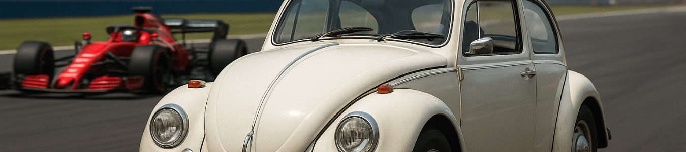 Ein heller VW Käfer fährt im Vordergrund auf einer Rennstrecke, während im Hintergrund unscharf ein roter Formel-1-Rennwagen zu sehen ist.