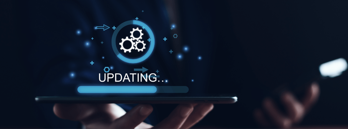 Eine Person hält ein Tablet in der Hand, über dem holografisch ein Ladekreis mit Zahnrädern, der Text „UPDATING...“ und ein blauer Fortschrittsbalken leuchten.