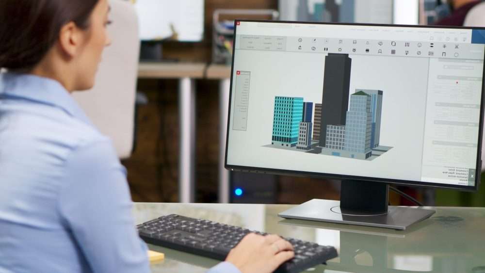 Young female architect working on computer with 3d building models. Architect working with modern technology.